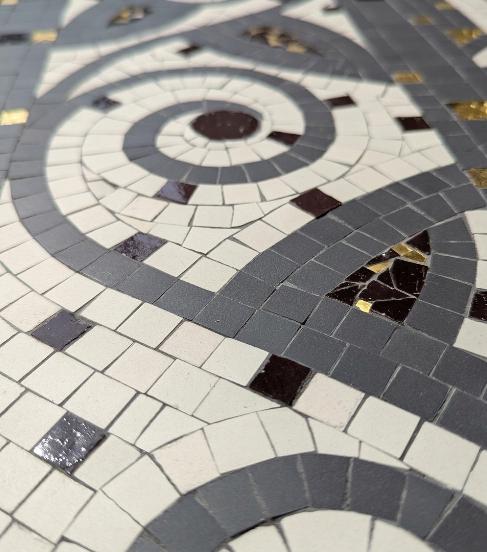 Abstract mosaic floor with concentric gray, white, black, and gold tile patterns